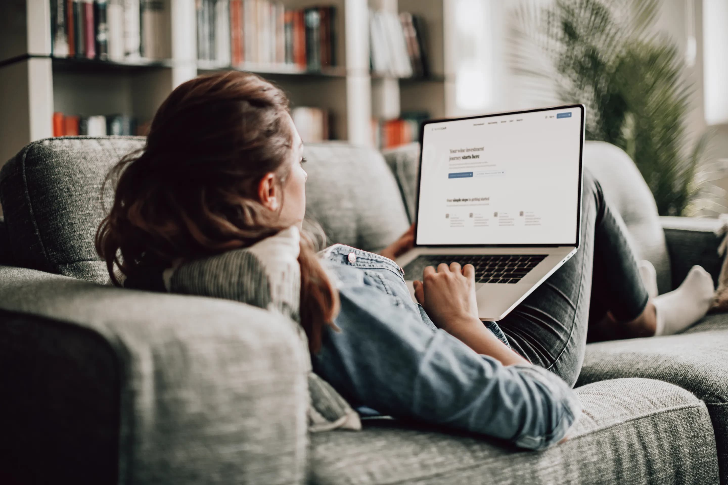 A woman on a sofa looking at the WineCap platform on her laptop
